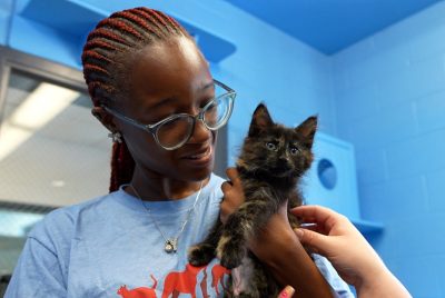 A female student holds a fluffy, black kitten.